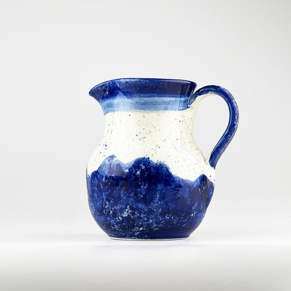 Blue ceramic jug with speckled white top and wave-style darker blue base