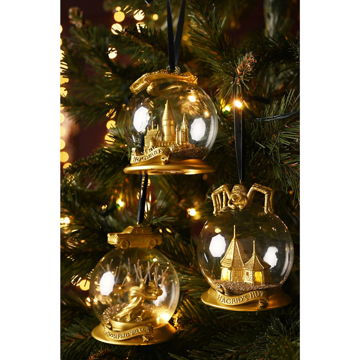 Set of three gold Whomping Willow LED bauble ornaments on a Christmas tree