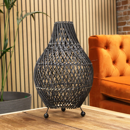 Black rattan table lamp with teardrop lattice shade on wooden tabletop