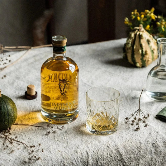 Amber whisky bottle with stopper and cut-glass tumbler on a table