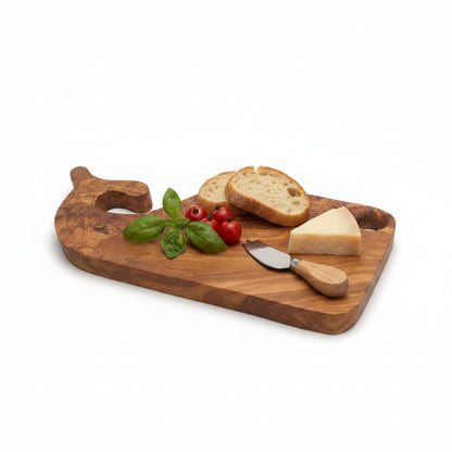 Fish-shaped wooden cutting and serving board with basil, tomatoes, bread, and knife