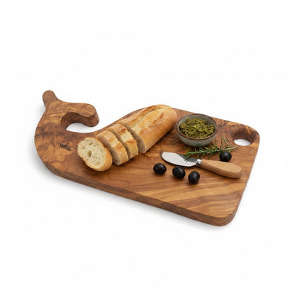 Fish-shaped wooden board with bread slices, olives, herbs, and butter knife