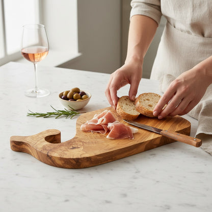 Fish-shaped wooden serving board with bread slices and prosciutto being prepared