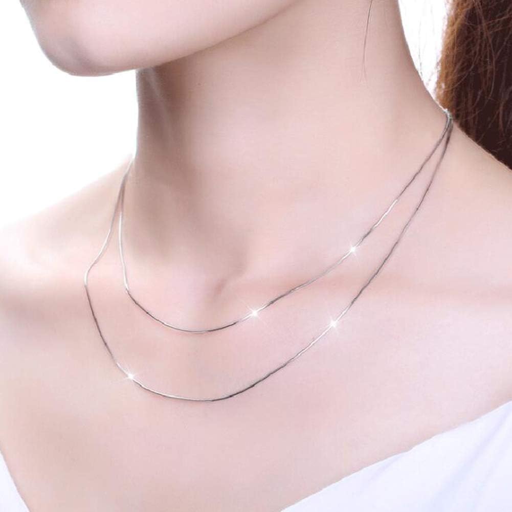 A close-up of a model's neck and upper chest wearing a delicate double-layered silver chain necklace.