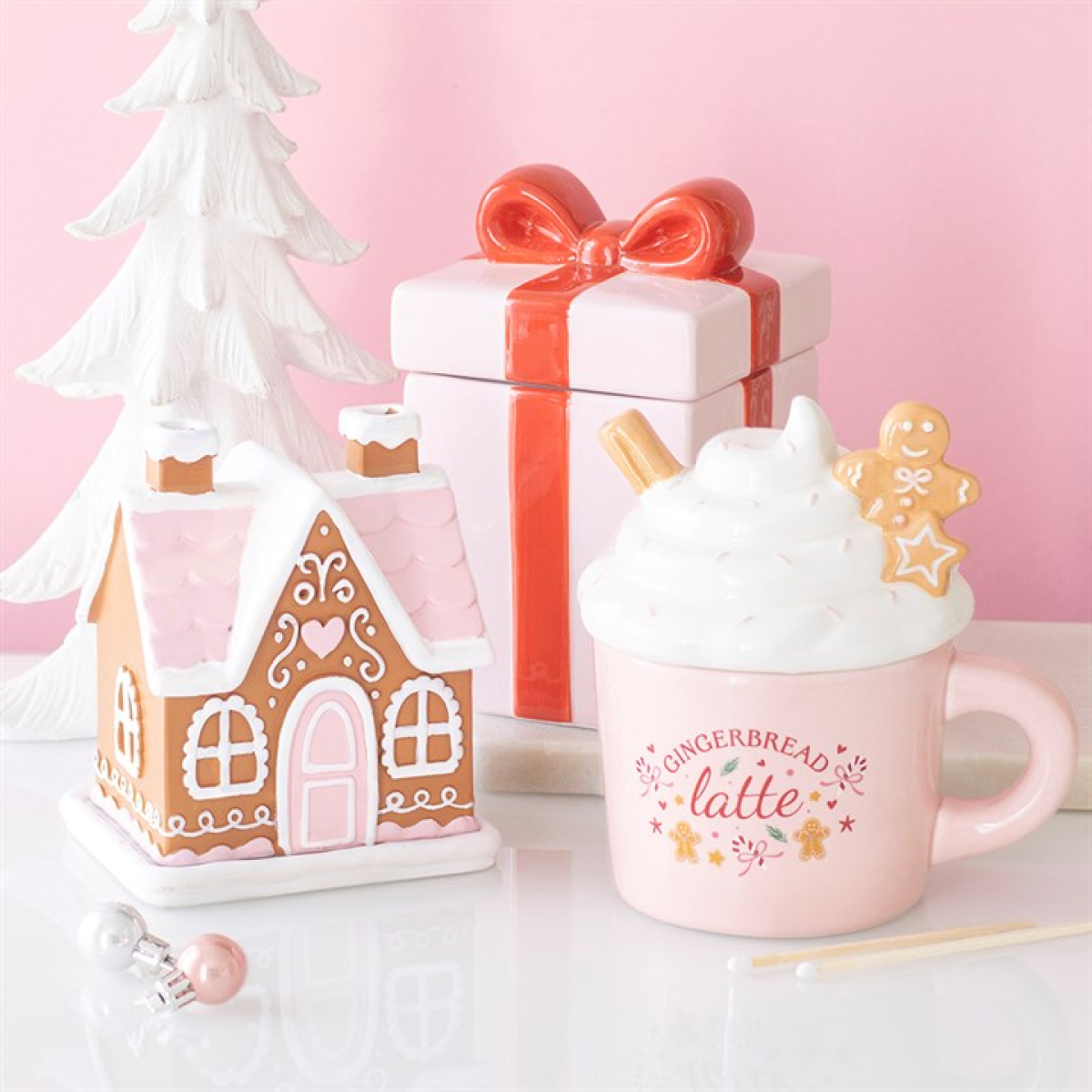 Pink gingerbread house incense cone burner beside pink ceramic gingerbread latte mug