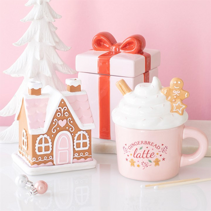 Pink gingerbread house incense cone burner beside pink ceramic gingerbread latte mug