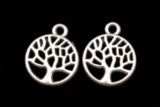 Three silver tree-of-life pendant charms with circular cutouts and top loops, shown on a solid black background.