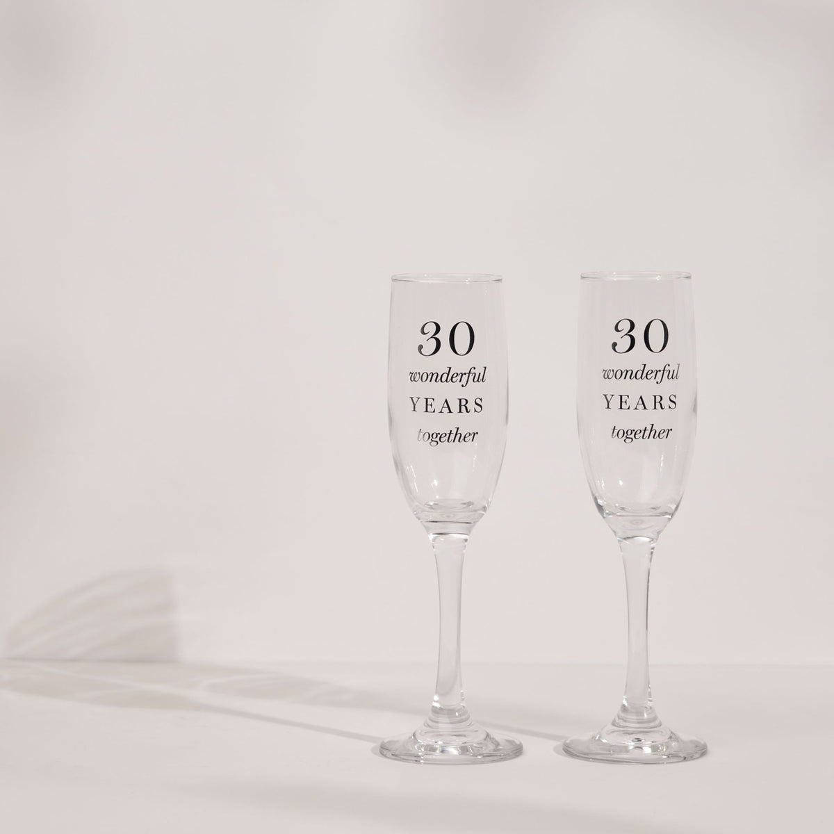 Two clear champagne flutes with '30 wonderful years together' text, slender bowls