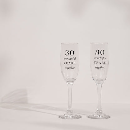 Two clear champagne flutes with '30 wonderful years together' text, slender bowls