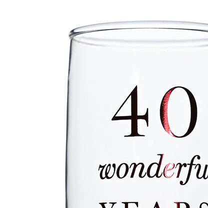 Close-up of clear champagne flute with black '40 wonderful' and red accent