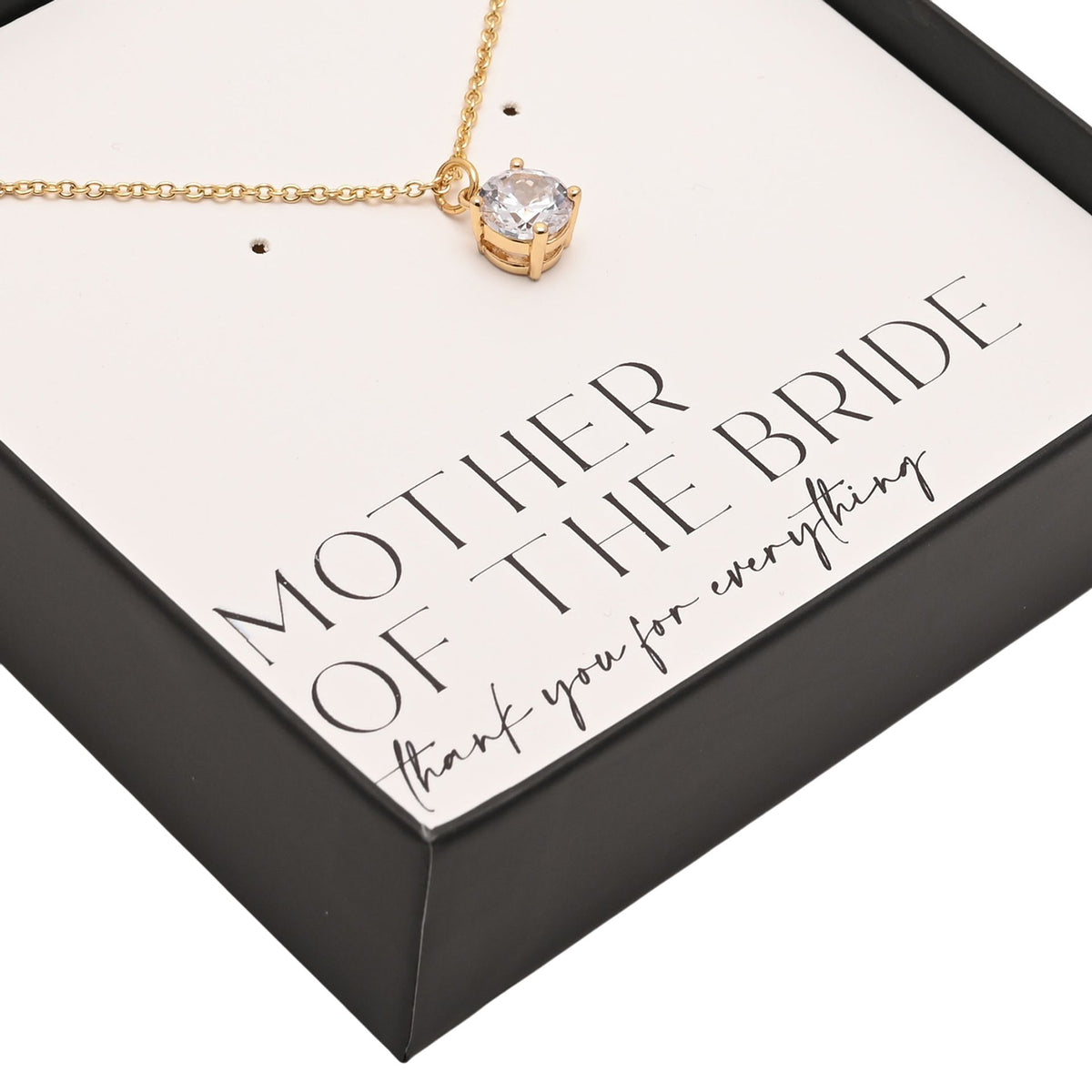 Close-up of gold chain and round crystal pendant on gift insert