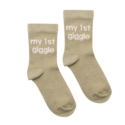 Pair of olive knit baby socks with "my 1st giggle" text on cuff
