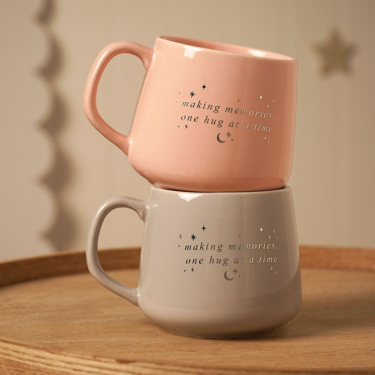 Stacked ceramic mugs with handles: pink and gray, each with “making memories” text