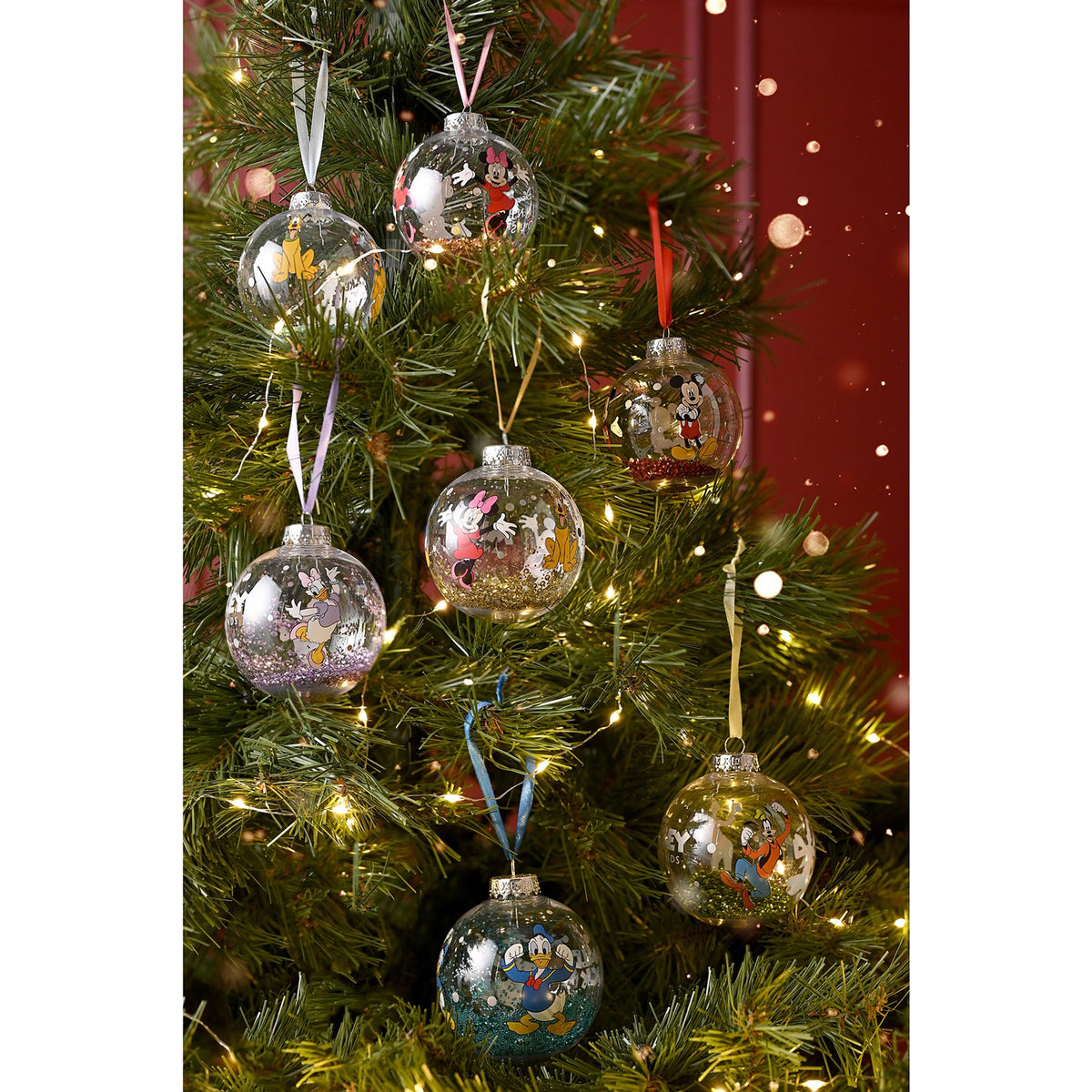 Mickey and Friends character baubles with gold glitter hanging on a Christmas tree