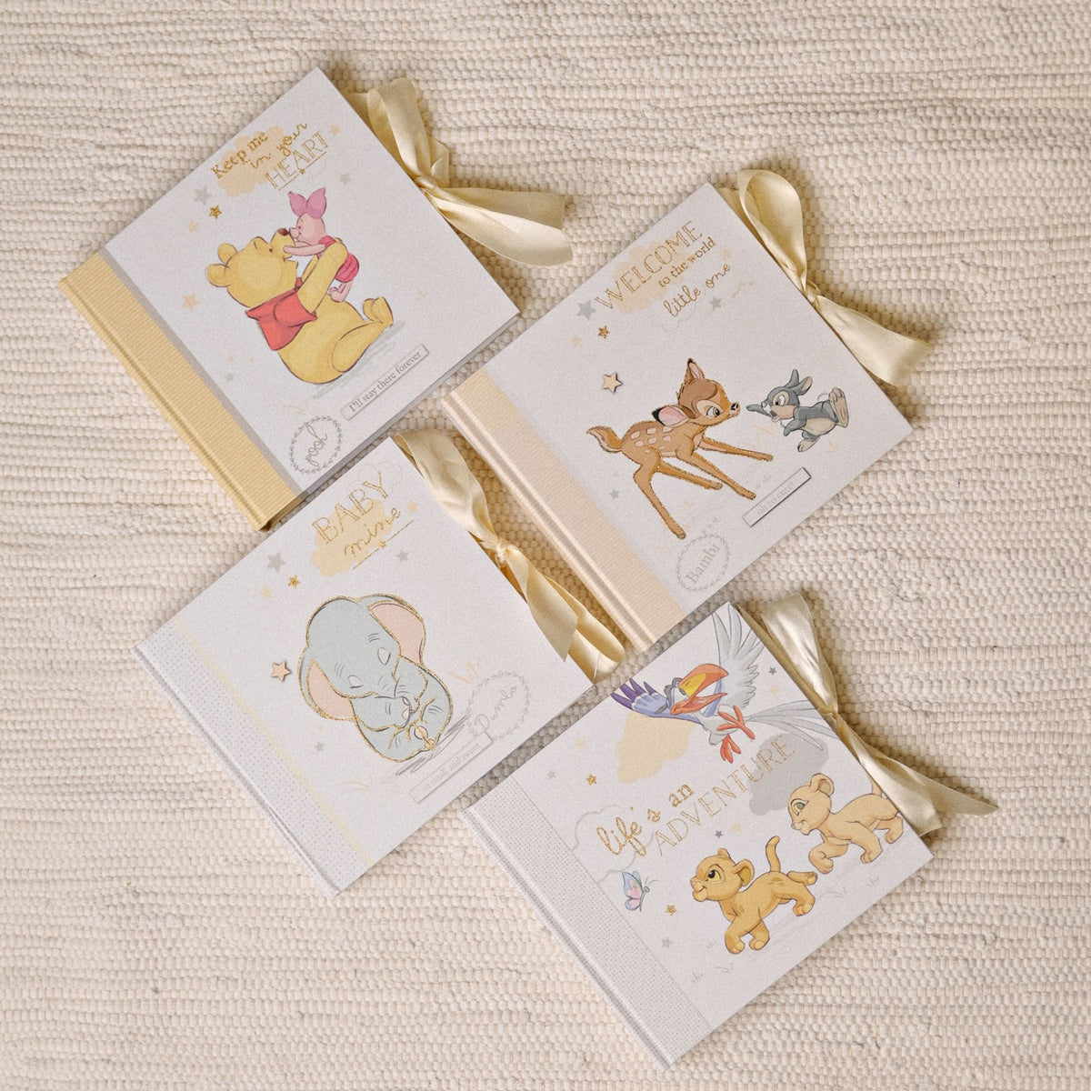 Assorted mini photo albums with Disney-themed baby illustrations and ribbon ties