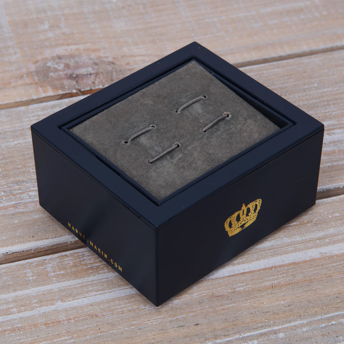 Car cufflinks laid out on gray insert in presentation box, metal posts visible