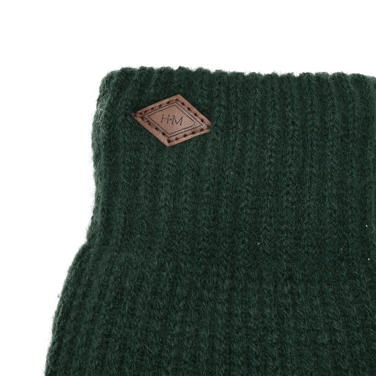 Close-up of green knitted glove with leather logo patch on cuff