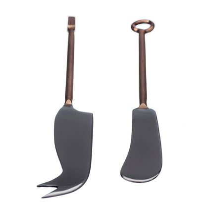 Two cheese knives with dark handles and copper-colored stems, curved for serving