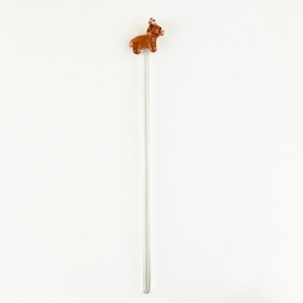 Clear glass drink stirrer with small brown cow figurine on top