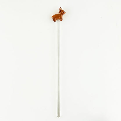 Clear glass drink stirrer with small brown cow figurine on top