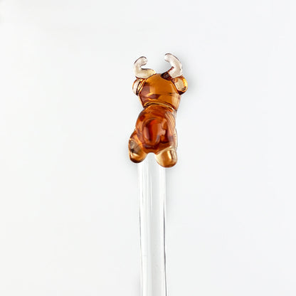 Clear glass drink stirrer topped with amber-brown cow figurine