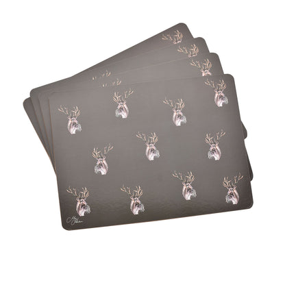Stack of four dark placemats with repeating stag head print in gold and white.