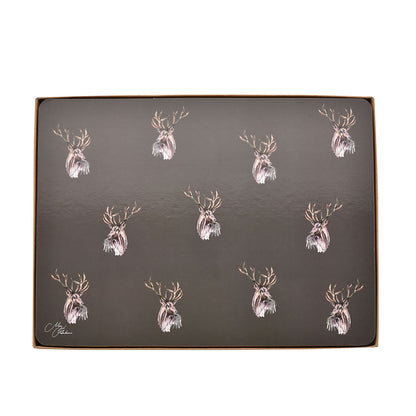 Boxed set of four dark placemats with repeating stag head motif in gold and white.