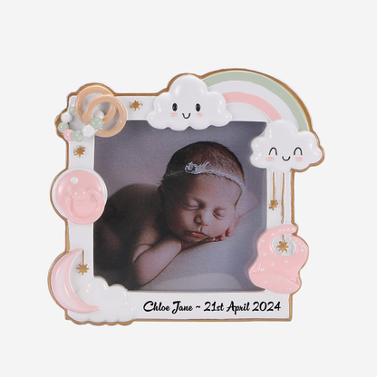Personalized baby photo frame holding a photo of a sleeping newborn baby, with a pastel rainbow, smiling clouds, moon, sun, and baby imagery. The frame has the name 'Chloe Jane' and the date '21st April 2024' written at the bottom, 