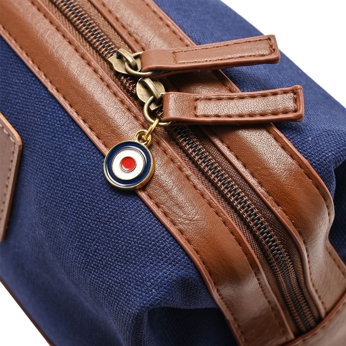 Closeup of brown faux leather zip pull and ring keychain on blue canvas washbag