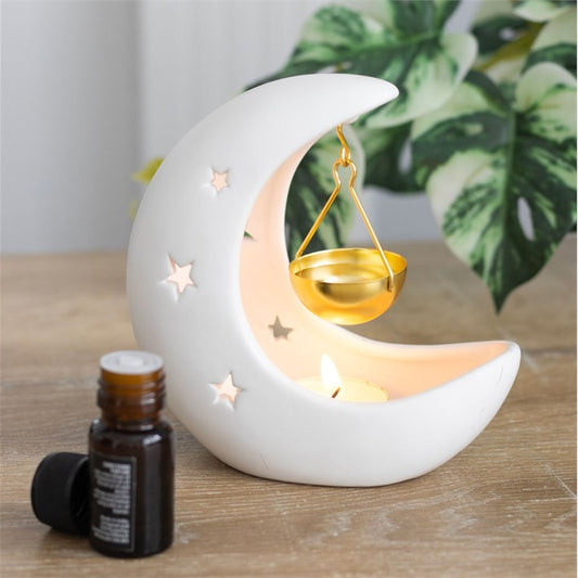 White crescent moon oil burner with gold hanging dish and lit candle inside