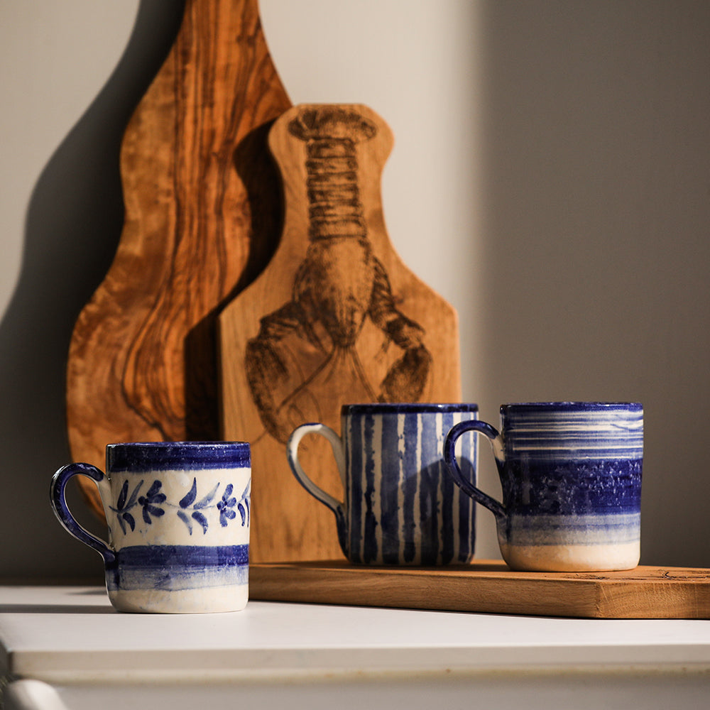 Three blue striped ceramic mugs with handles, varied stripe patterns