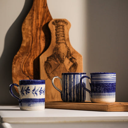 Three blue striped ceramic mugs with handles, varied stripe patterns