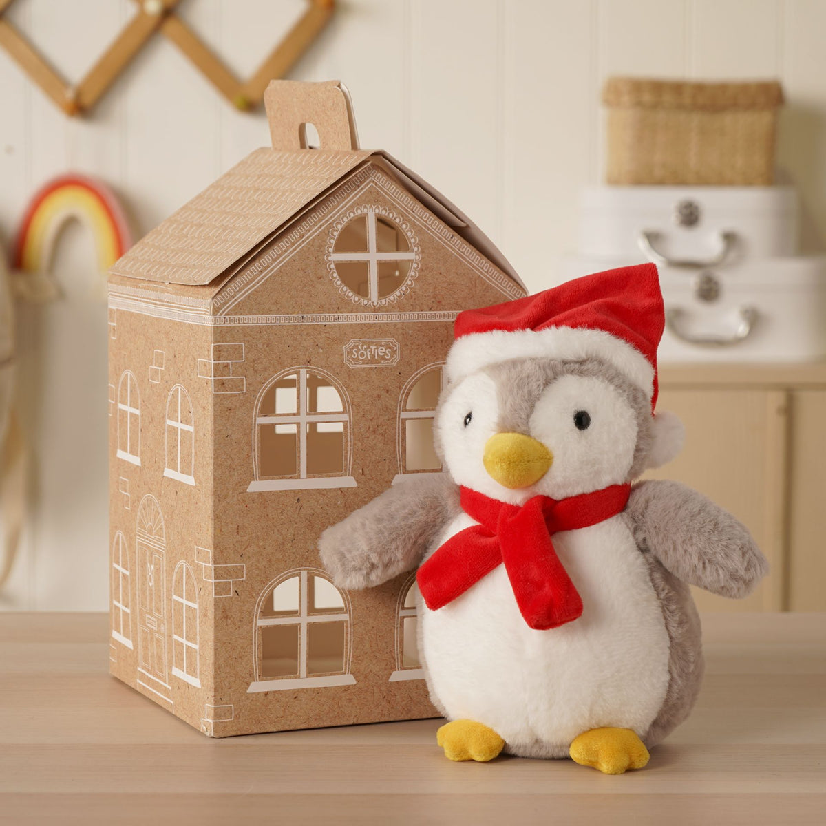Plush Christmas penguin with red Santa hat and red scarf, standing on a tabletop
