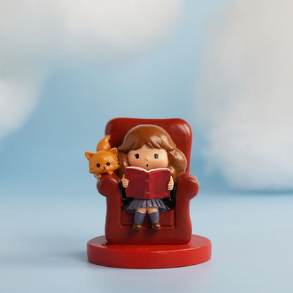 Red armchair figurine: girl holding a red book with small orange pet beside