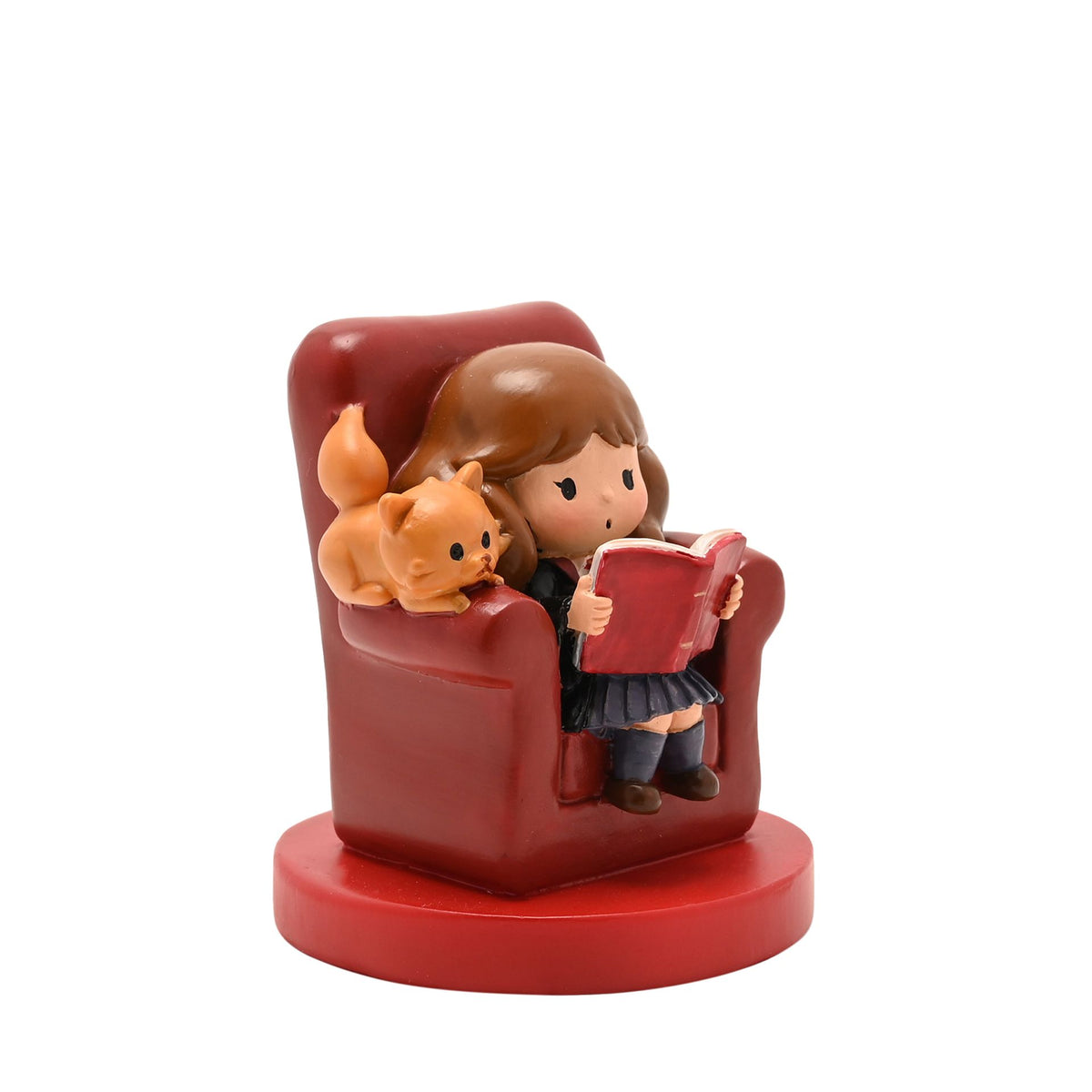 Red armchair figurine with girl reading a red book beside a small orange pet