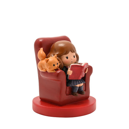 Red armchair figurine with girl reading a red book beside a small orange pet