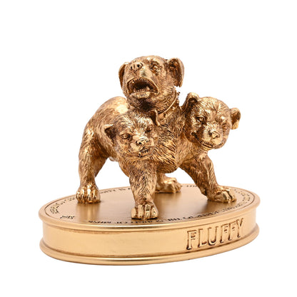 Three-headed dog figurine in gold tone, standing on round base labeled “FLUFFY”.