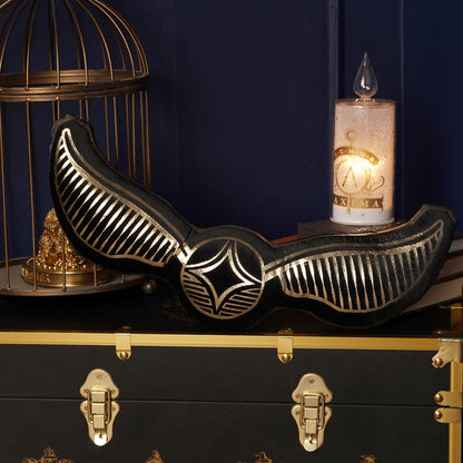Velvet snitch-shaped cushion with black wing design and gold-striped edges