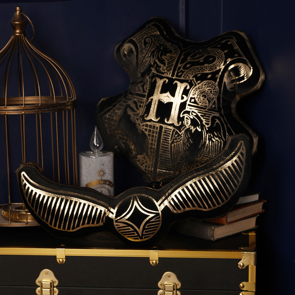Snitch-shaped velvet cushion with Hogwarts-style crest and gold-wing stripe design