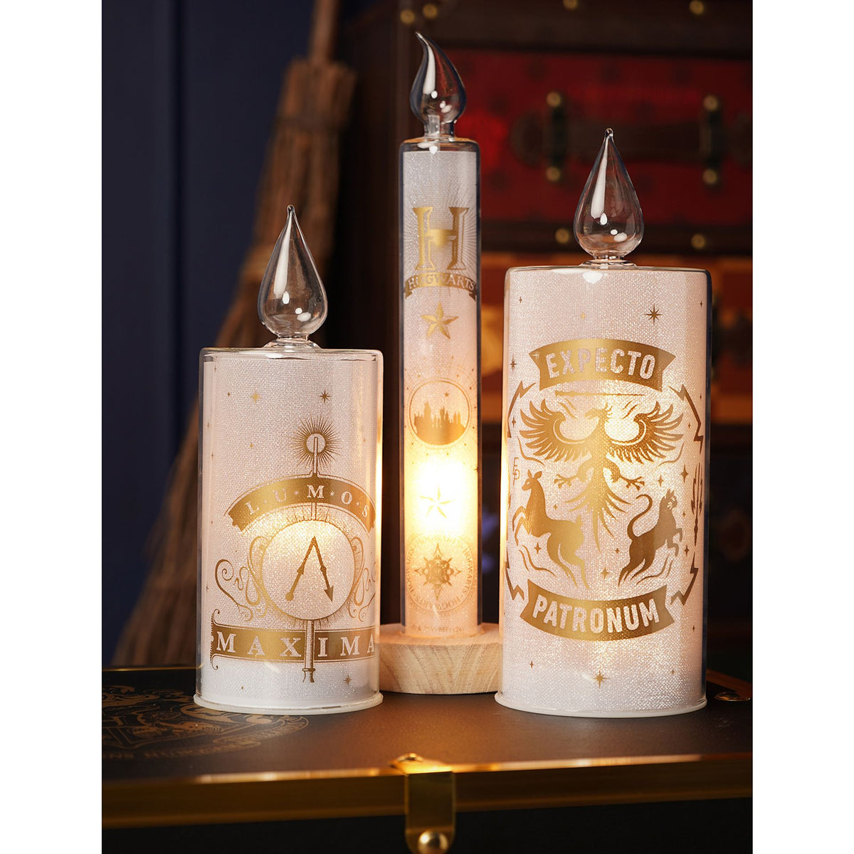 Set of three LED candles with wizard crest prints and clear flame tops, each on wooden bases