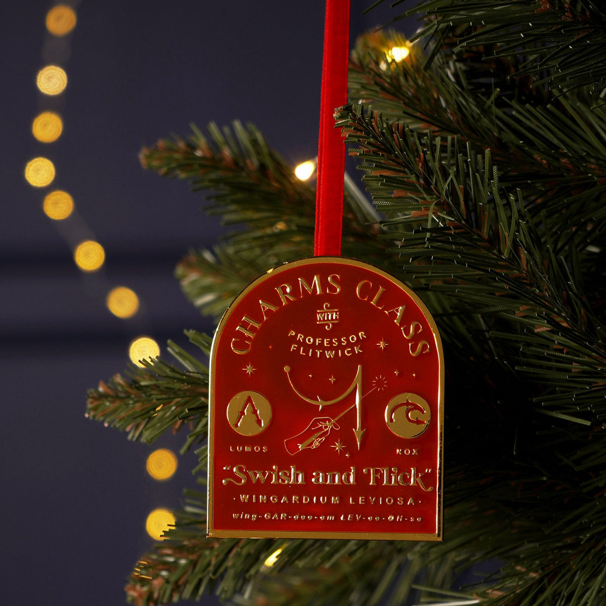 Round metal hanging charm, brown-and-gold crest with red ribbon, "Swish and Flick"