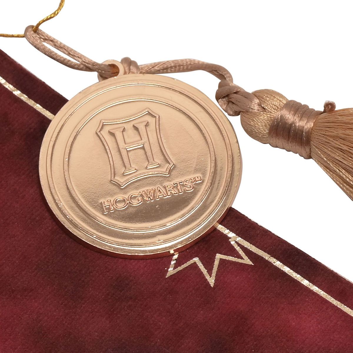 Gryffindor hanging banner close-up of round gold charm with tassel on maroon fabric