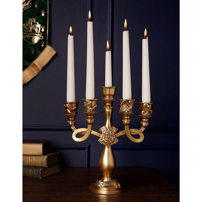 Gold-toned resin candelabra with five lit white candles and Hogwarts-style base