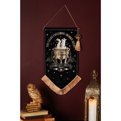 Black hanging banner with gold cauldron crest, star icons, tan fringe and tassel
