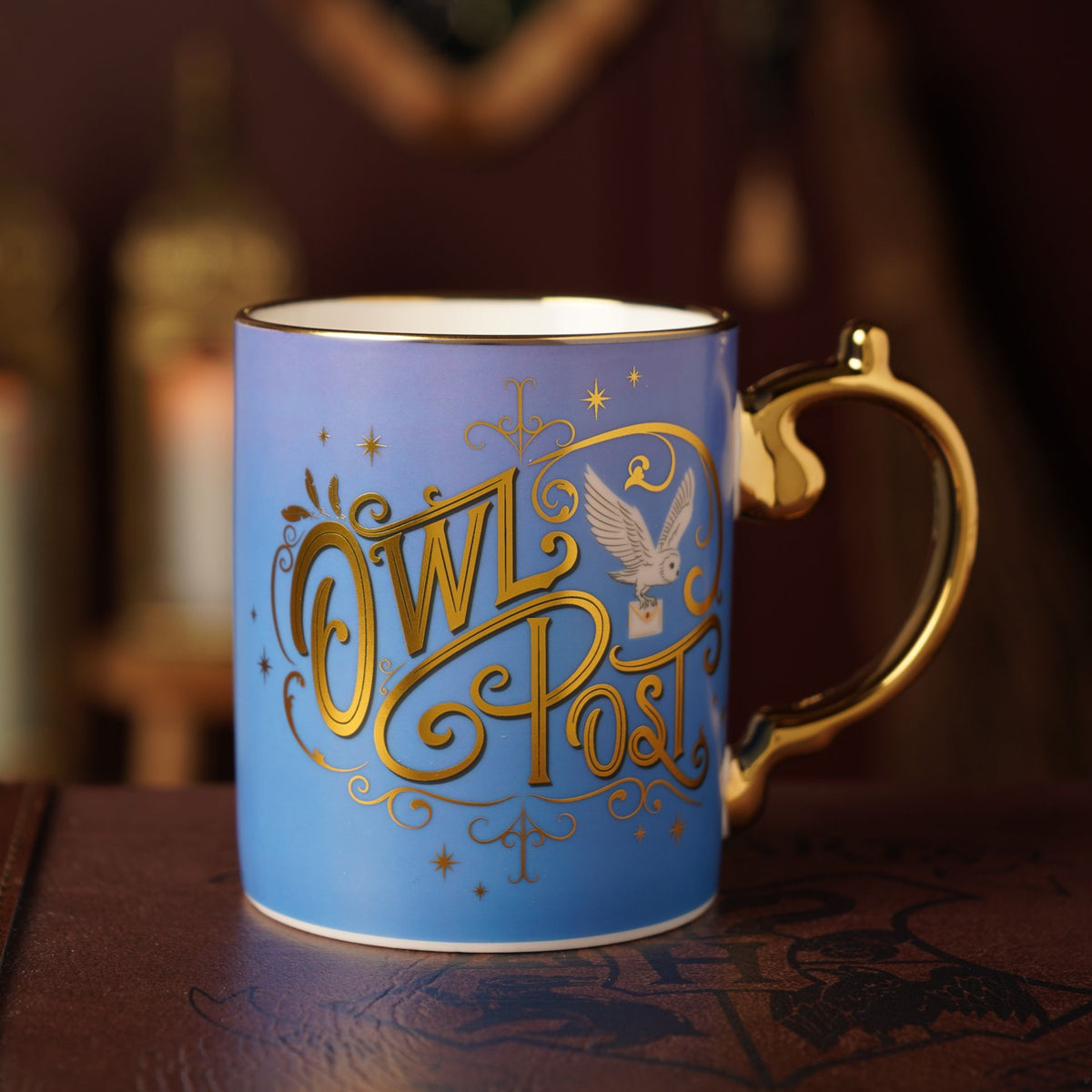 Blue ceramic mug with gold handle and Owl Post crest, white interior.