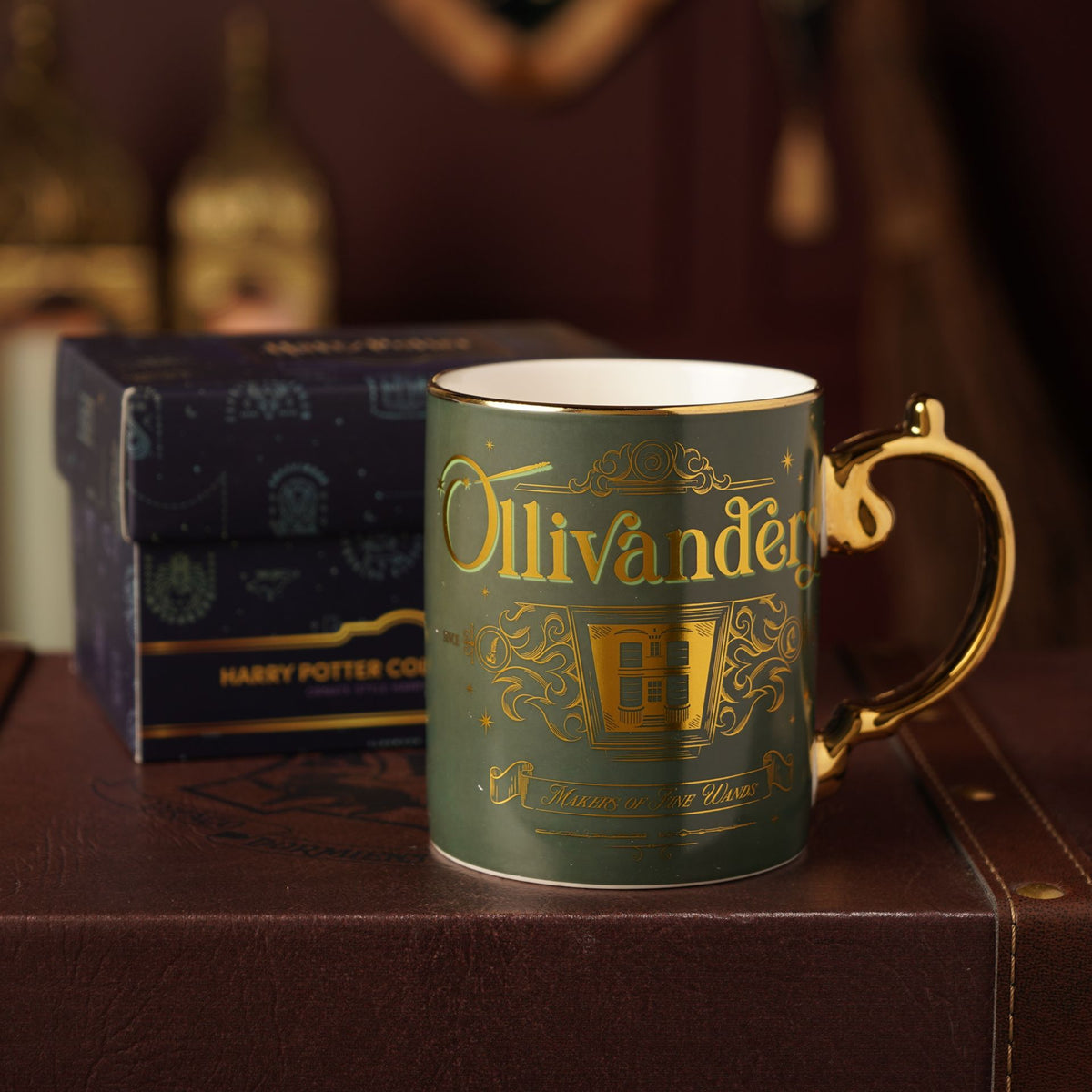 Dark green collectible mug with gold “Ollivanders” design, gold handle, and box