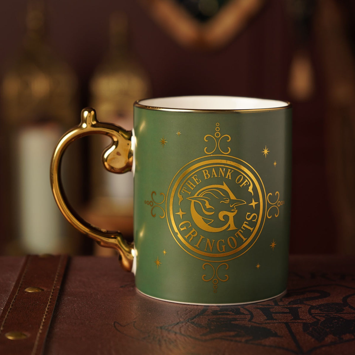 Green collectible mug with gold Bank of Gringotts emblem, stars, and decorative frame