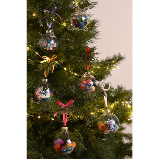 Seven Stitch Christmas baubles with pom-pom details hanging on a decorated tree