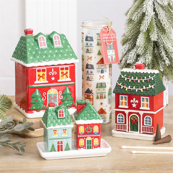 Christmas street print tube candle in clear jar beside Christmas house figurines