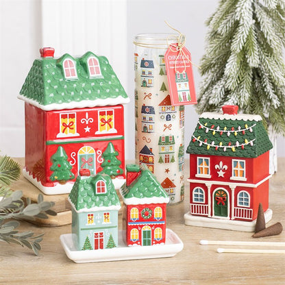 Christmas street print tube candle in clear jar beside Christmas house figurines